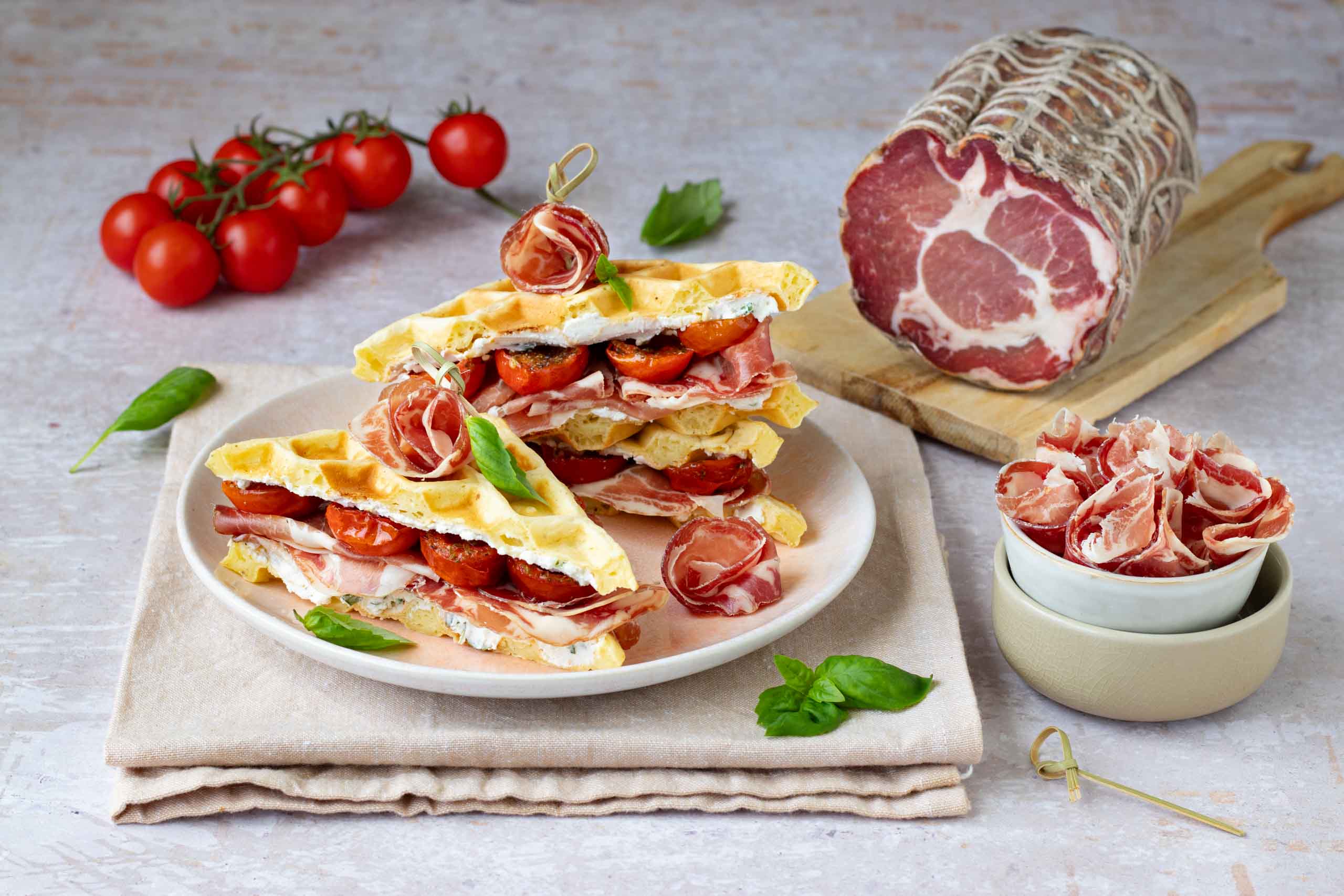 Sandwich di waffles salati con crema di ricotta al basilico, pomodorini confit e Coppa di Parma IGP